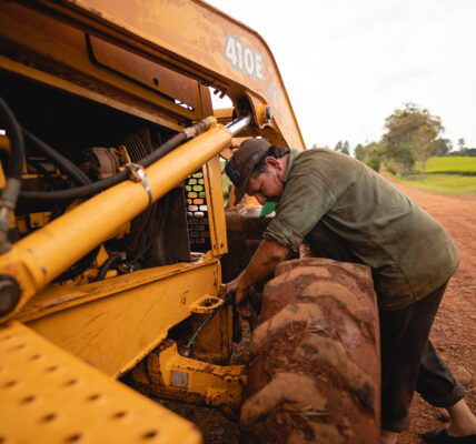 Agricultor realizando mantenimiento a maquinaria en un camino rural, como parte del trabajo de campo y adaptación tecnológica.