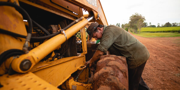 Agricultor realizando mantenimiento a maquinaria en un camino rural, como parte del trabajo de campo y adaptación tecnológica.