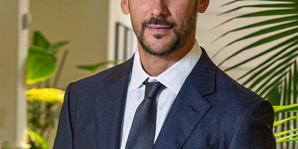 Joaquín Basanta, presidente de Agro Sustentable, viste traje oscuro y corbata en un entorno con plantas, representando liderazgo en bioeconomía.