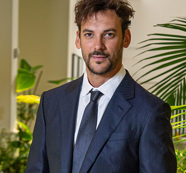 Joaquín Basanta, presidente de Agro Sustentable, viste traje oscuro y corbata en un entorno con plantas, representando liderazgo en bioeconomía.