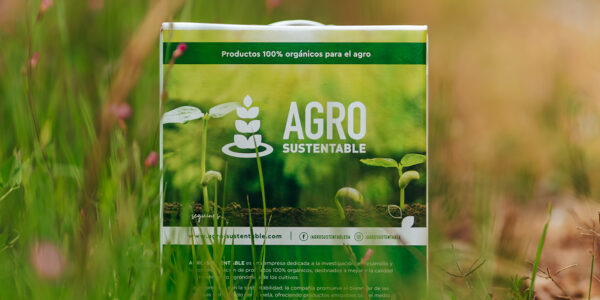 Envase de Agro Sustentable con diseño verde y lema “Productos 100% orgánicos para el agro”, ubicado entre pasto natural, simbolizando el compromiso ambiental de la empresa.