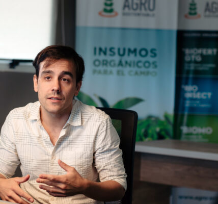 Matías Imperiale habla en una oficina sobre prácticas agrícolas sustentables, con afiches de Agro Sustentable de fondo.