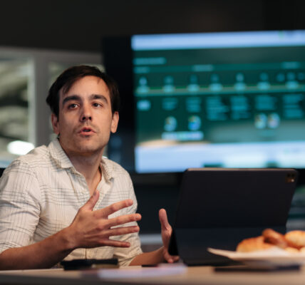 Matías Imperiale, ingeniero agrónomo y referente en bioinsumos, hablando en una reunión con una computadora portátil y una pantalla de presentación de fondo.