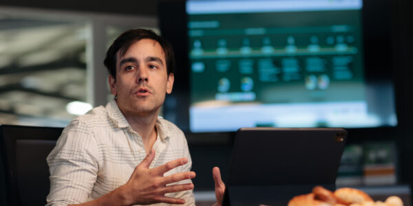 Matías Imperiale, ingeniero agrónomo y referente en bioinsumos, hablando en una reunión con una computadora portátil y una pantalla de presentación de fondo.