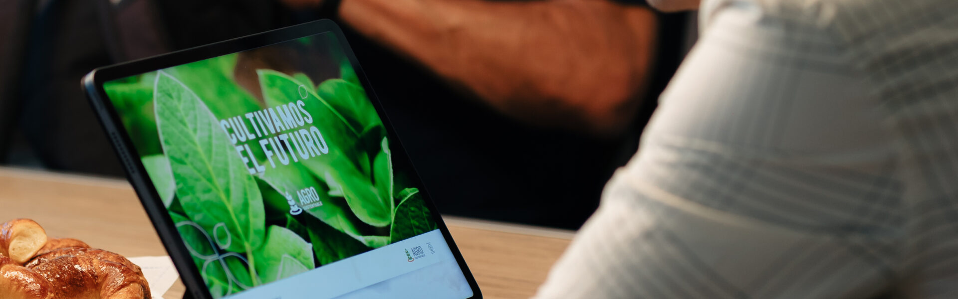 Hombre utilizando una notebook con pantalla que muestra el mensaje “Cultivamos el futuro” de Agro Sustentable, durante una reunión.