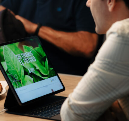 Hombre utilizando una notebook con pantalla que muestra el mensaje “Cultivamos el futuro” de Agro Sustentable, durante una reunión.