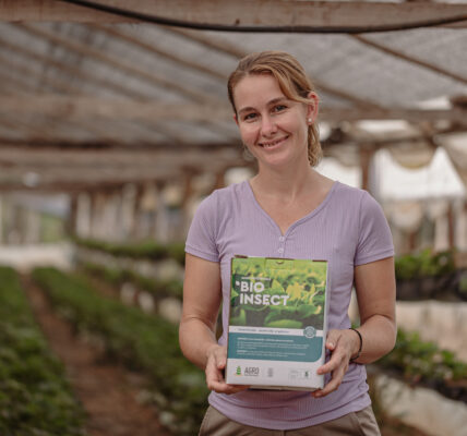 Productora rural sostiene una caja de BIOINSECT en un invernadero, mostrando su compromiso con prácticas agrícolas ecológicas promovidas por Agro Sustentable.