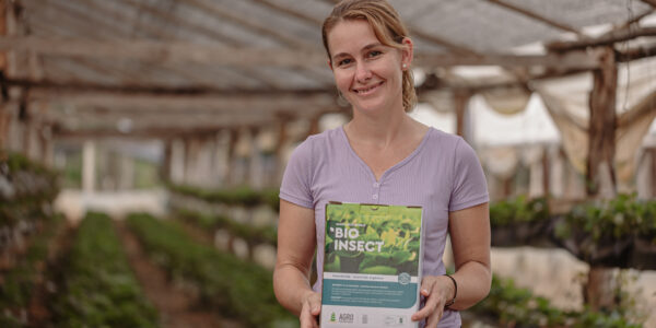 Productora rural sostiene una caja de BIOINSECT en un invernadero, mostrando su compromiso con prácticas agrícolas ecológicas promovidas por Agro Sustentable.