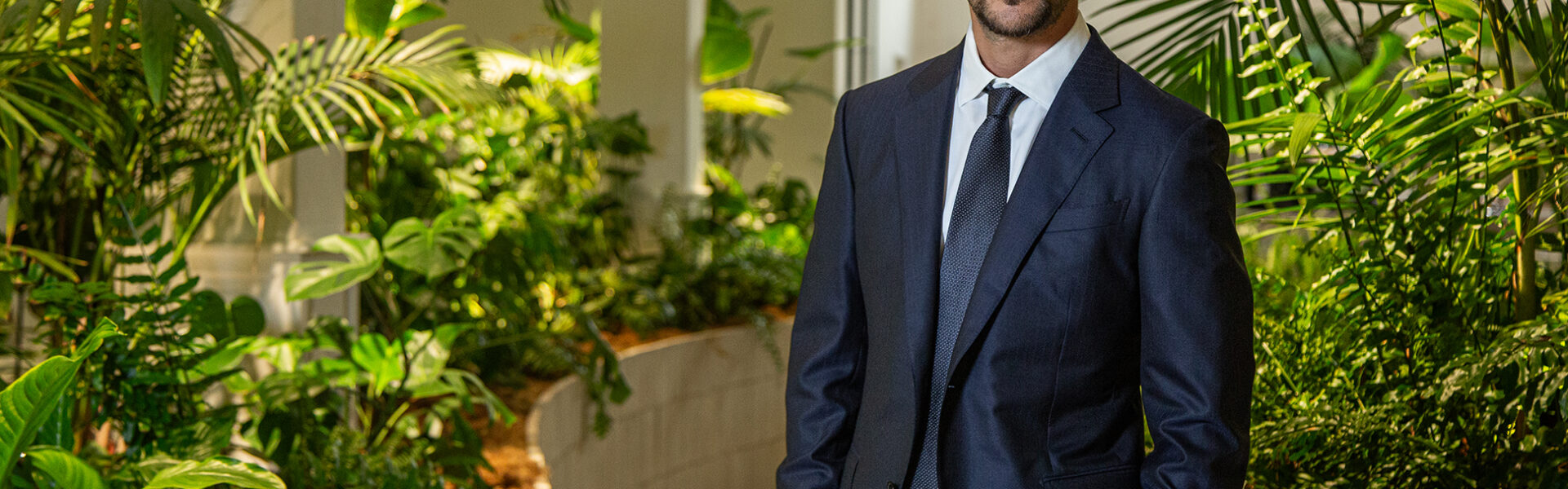 Joaquín Basanta, de traje oscuro, posa en un espacio interior rodeado de vegetación tropical y luz natural, transmitiendo profesionalismo y compromiso ambiental.