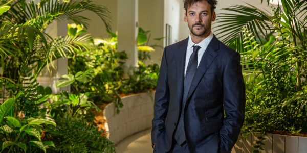 Joaquín Basanta, de traje oscuro, posa en un espacio interior rodeado de vegetación tropical y luz natural, transmitiendo profesionalismo y compromiso ambiental.