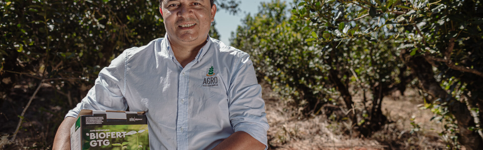 Agricultor sostiene BIOFERT GTG X de Agro Sustentable en un cultivo, destacando su uso en la producción de tomate orgánico.