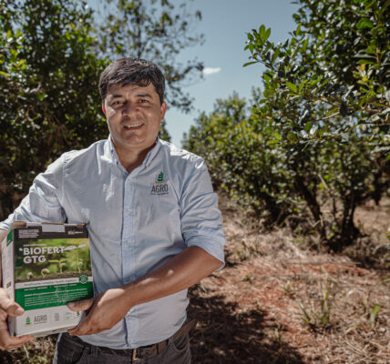 Agricultor sostiene BIOFERT GTG X de Agro Sustentable en un cultivo, destacando su uso en la producción de tomate orgánico.