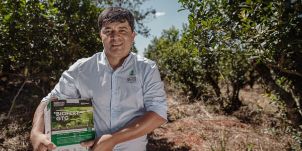 Agricultor sostiene BIOFERT GTG X de Agro Sustentable en un cultivo, destacando su uso en la producción de tomate orgánico.